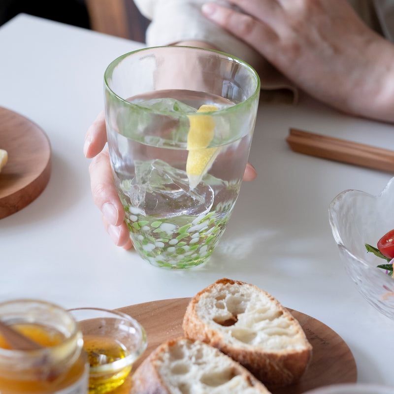 津軽びいどろ 津軽自然色りんご あおりんごタンブラー レモン水が注がれたグラスを手で持っている画像