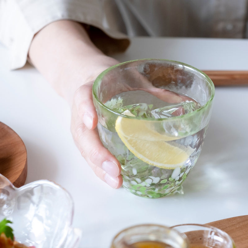 津軽びいどろ 津軽自然色りんご あおりんごカップ レモン水が注がれたグラスを手で持っている画像