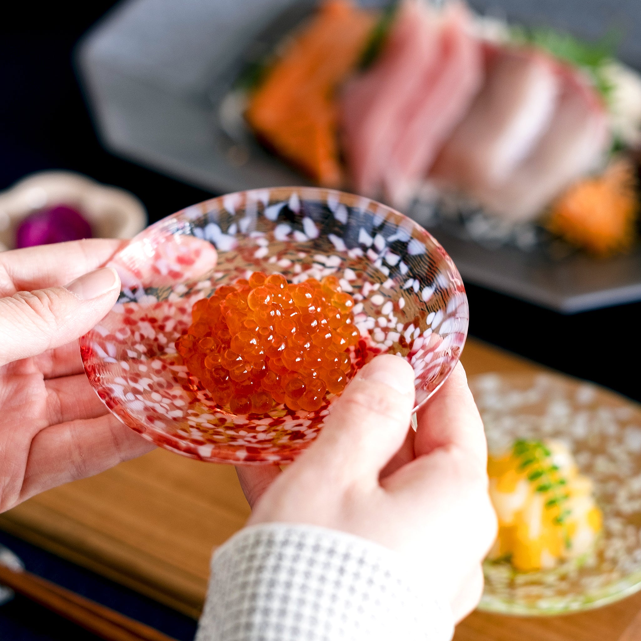 津軽びいどろ 豆皿ギフト  りんご豆皿ペアセット いくらがよそわれたガラス食器を手で持ち上げている画像