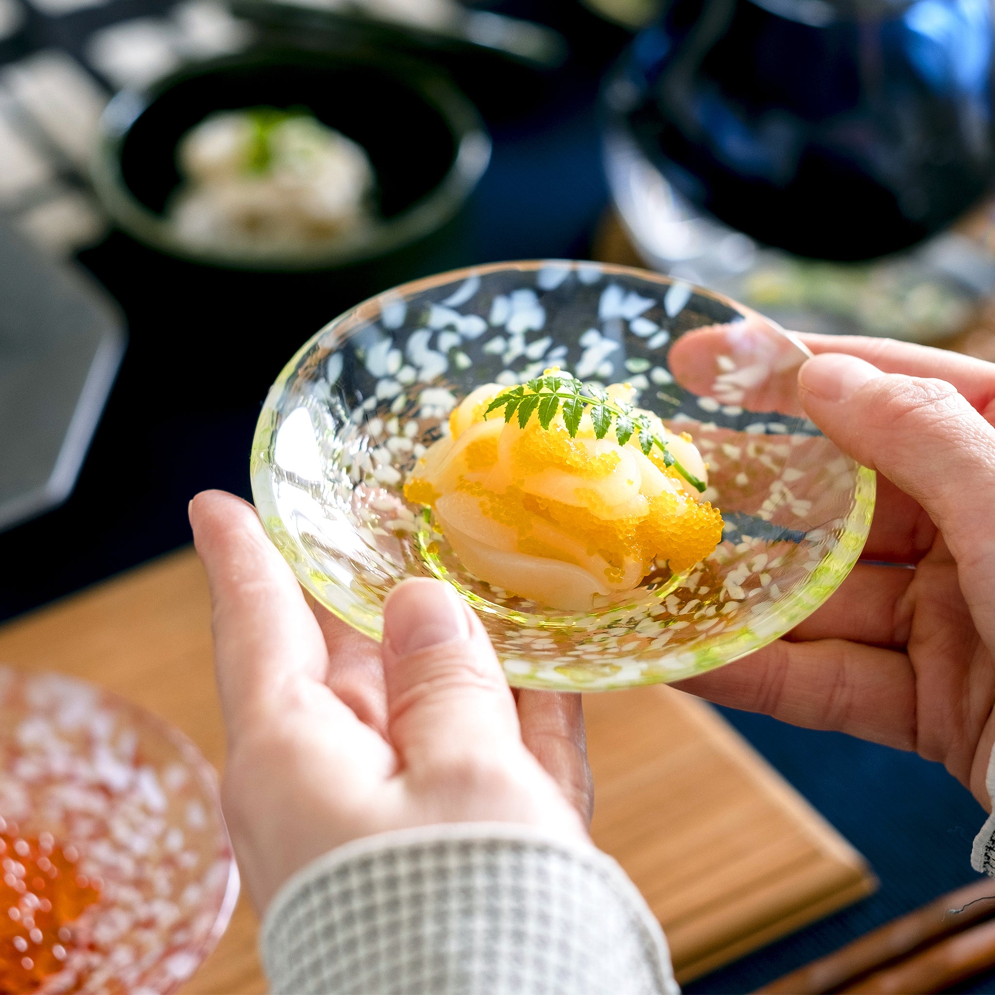 津軽びいどろ 豆皿ギフト  りんご豆皿ペアセット 料理がよそわれたガラス食器を手で持ち上げている画像