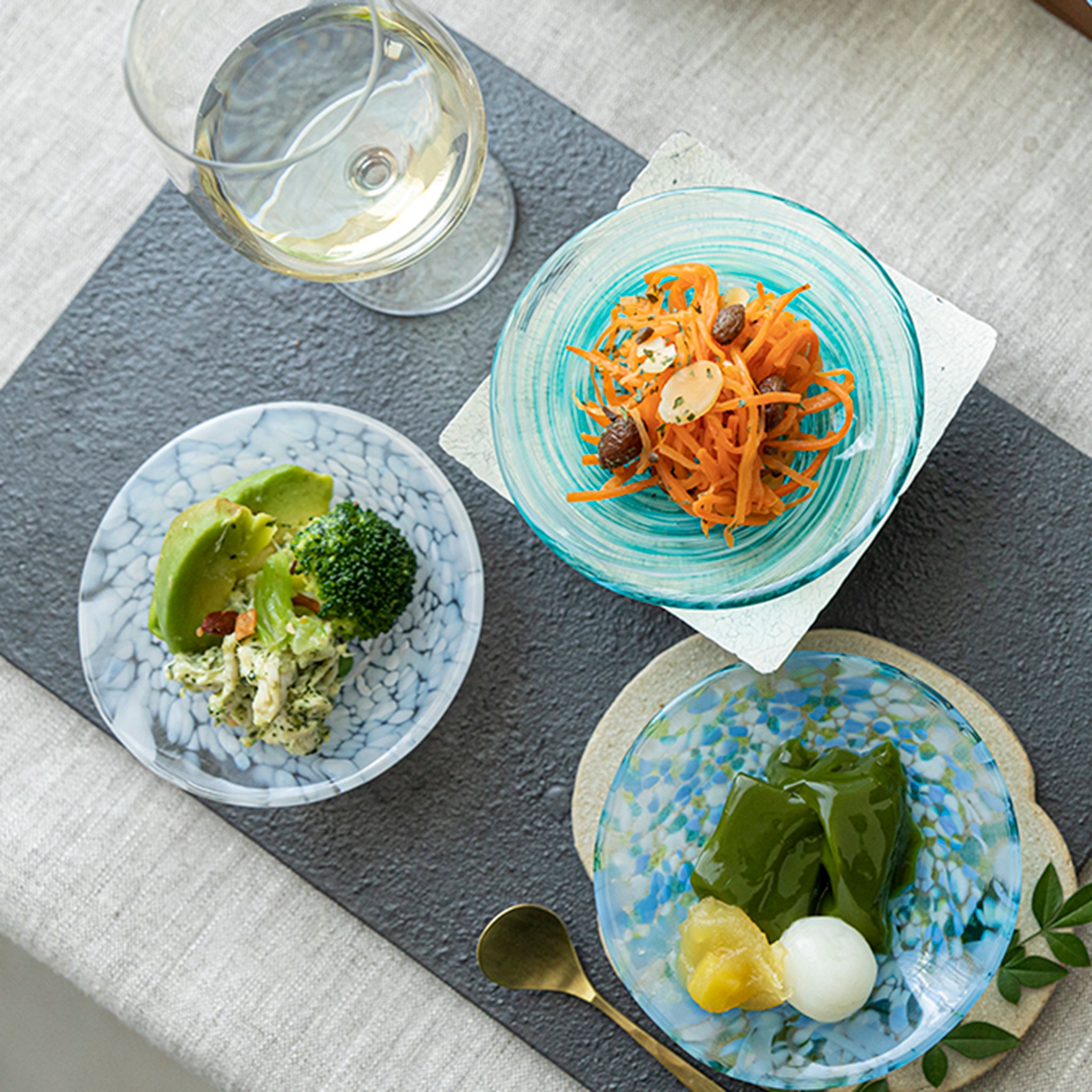 津軽びいどろ 色色豆皿 淡雪 料理が乗った小皿が食卓に並んでいる画像