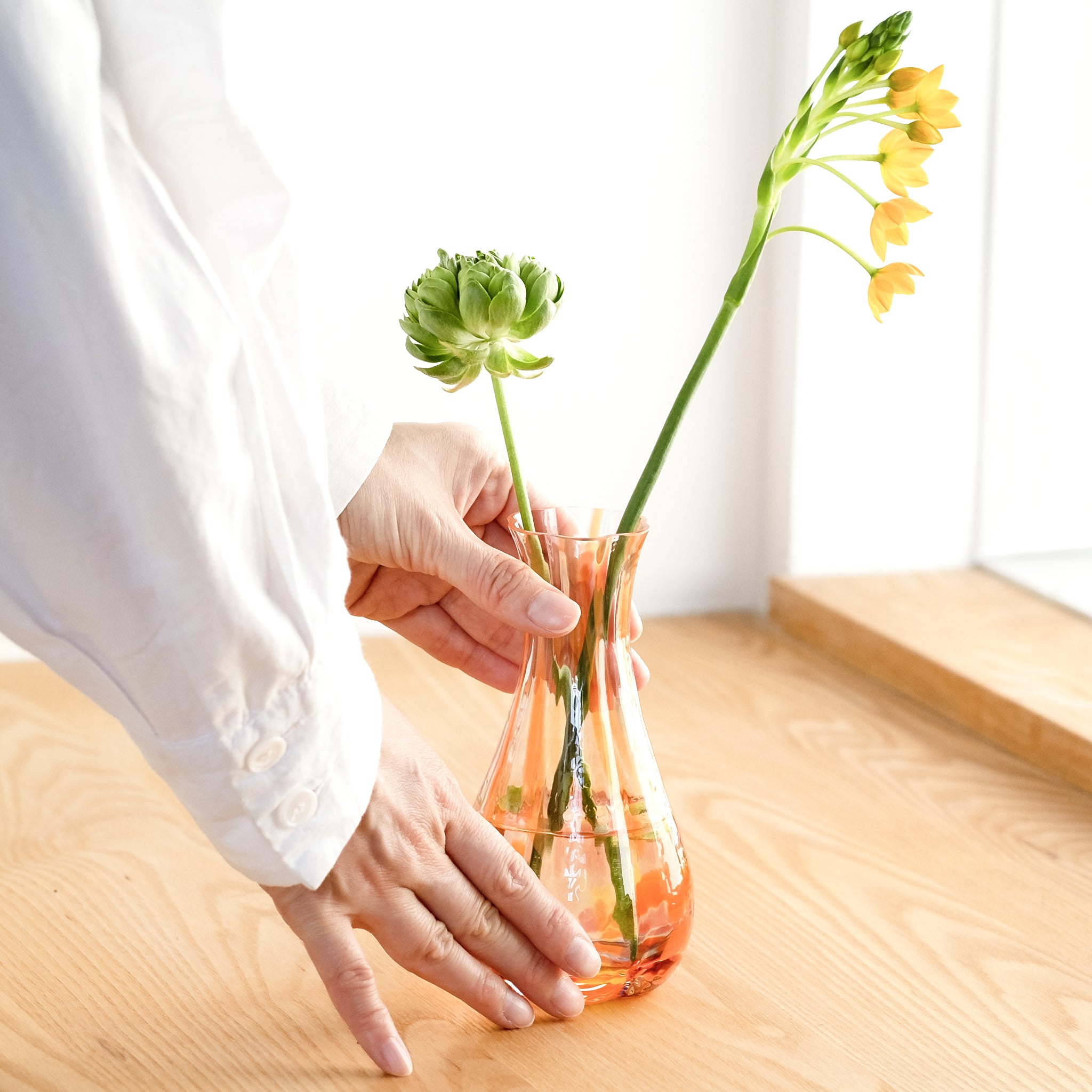 津軽びいどろ 花ひかり サンセットオレンジ 一輪挿し  手を添えたイメージ画像