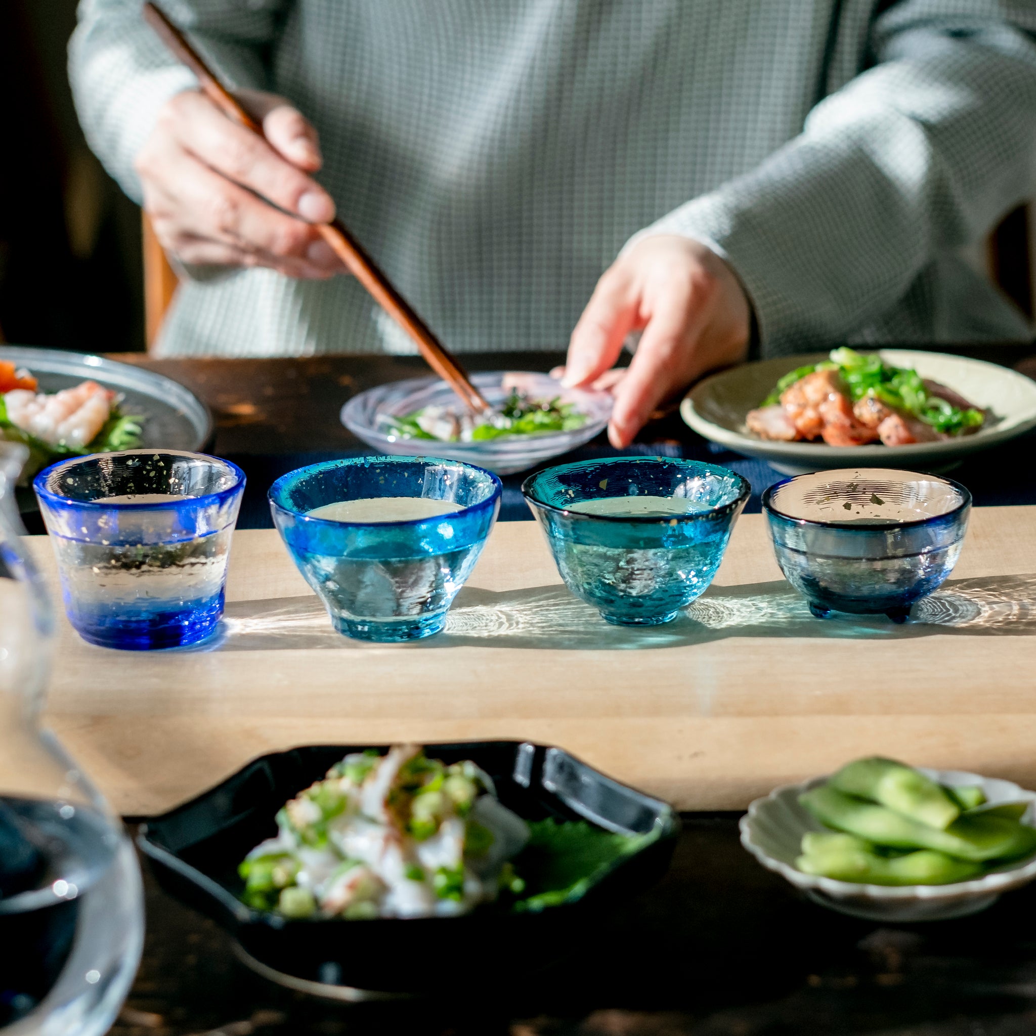 津軽びいどろ あおもりの海 盃 太平洋 色違いの盃が食卓に並んでいる画像