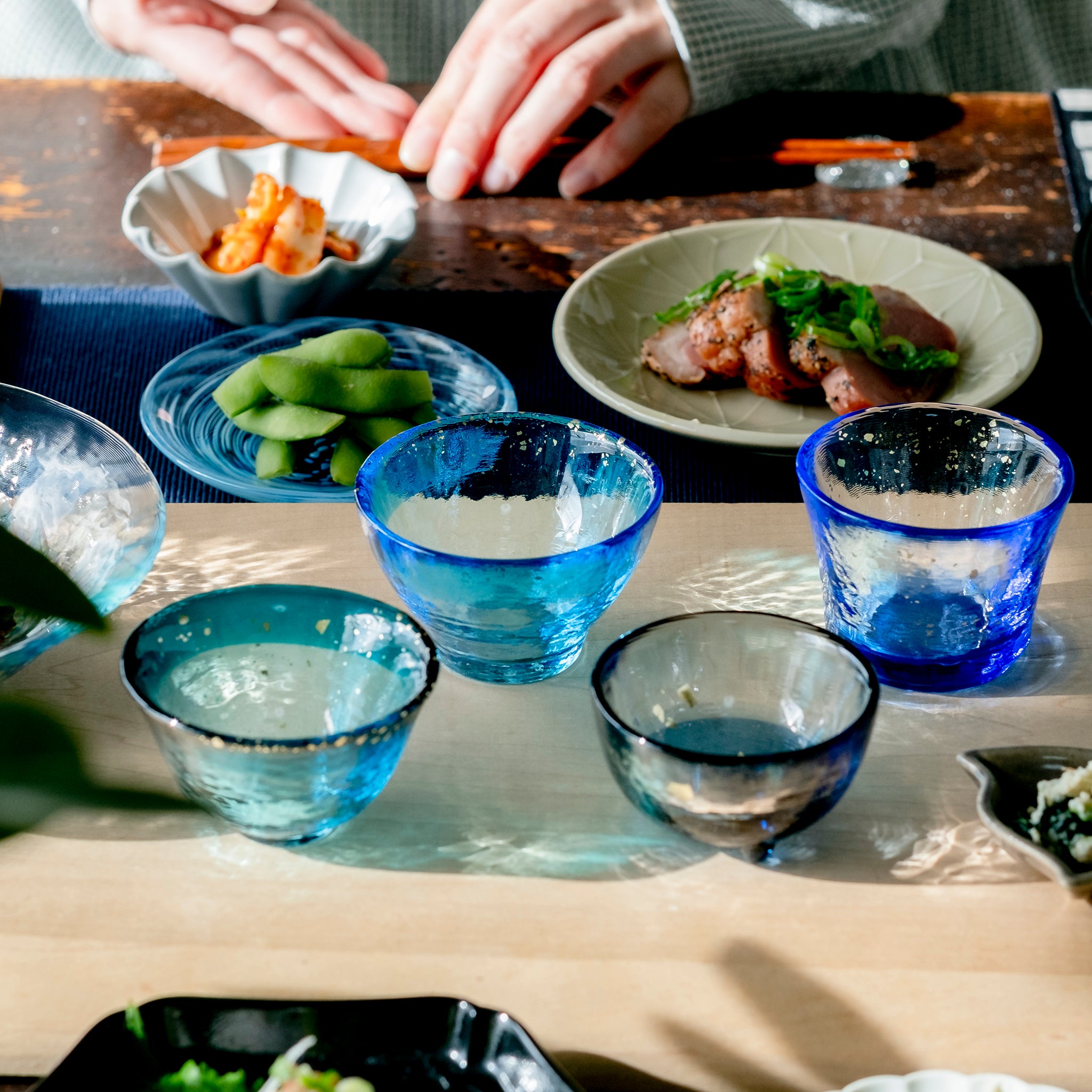  津軽びいどろ あおもりの海 盃 津軽海峡 色違いの盃が食卓に並んでいる画像